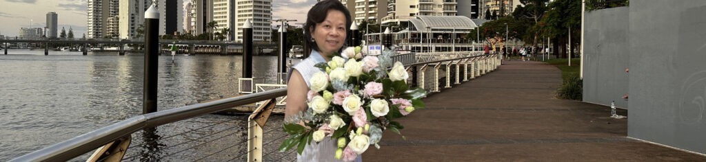 A woman holding a bouquet of flowers near the water, creating a serene and picturesque scene